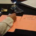 A participant writing priorities on paper. One of them says: "Participate in candidate forums on elections." 